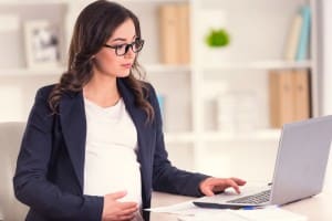 A young pregnant woman looking at a computer