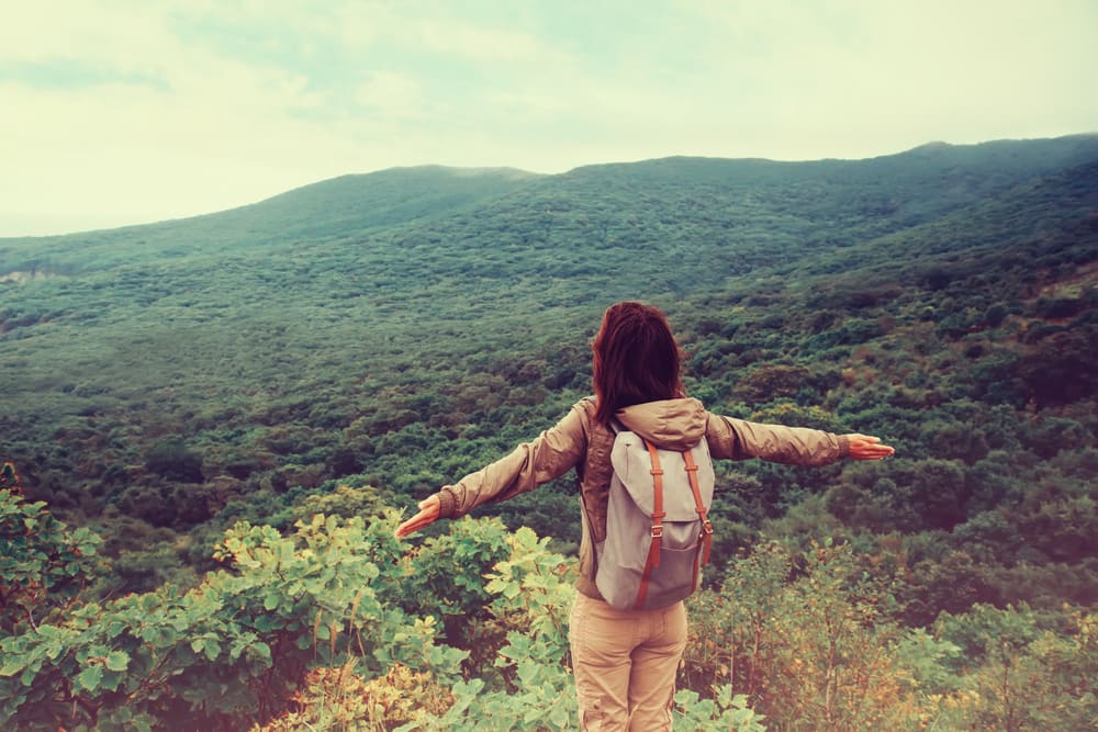 Female hiker with arms spread out overlooking the hillside