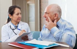 Doctor taking note while talking to older man about cataract surgery recovery