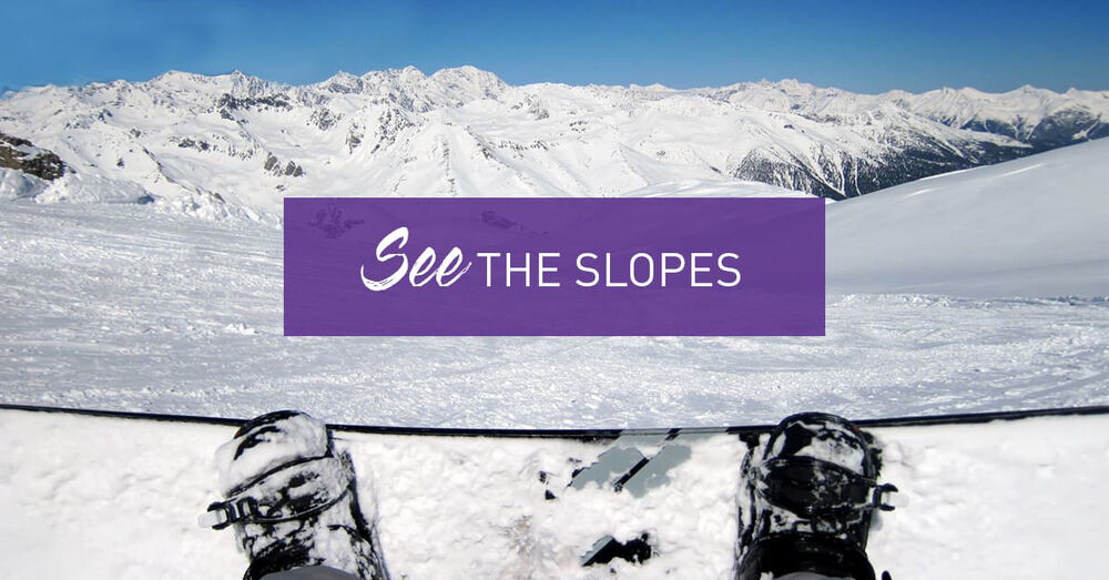 snowboarders feet on board overlooking the snowy mountains - See The Slopes Graphic