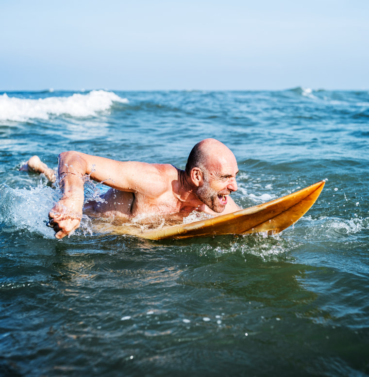 middle aged man surfing in the ocean