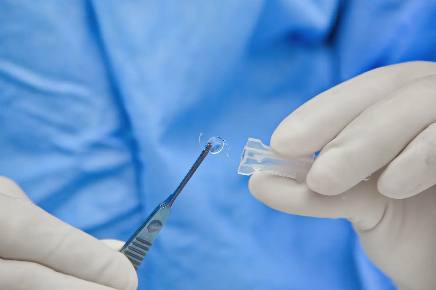 close up of doctor holding an intraocular lens with forceps