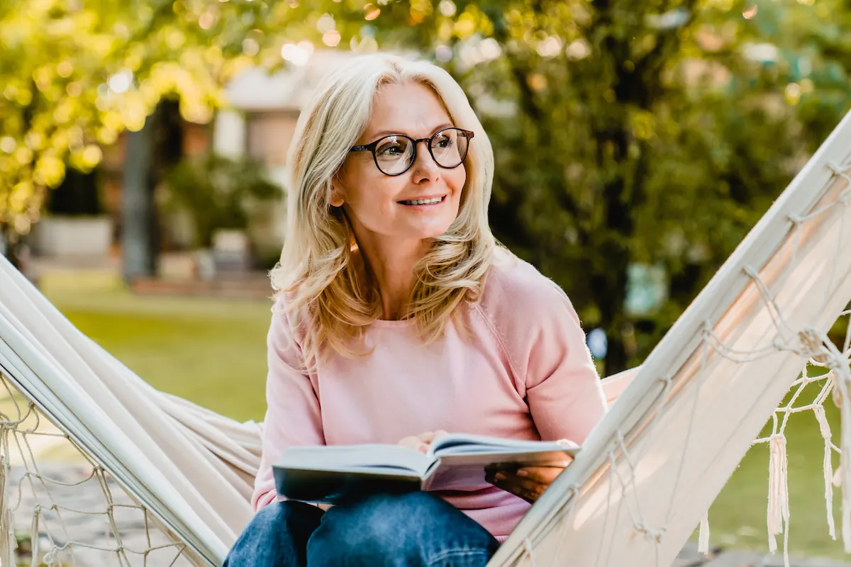 mature woman wearing reading glasses and holding book. vision correction candidate